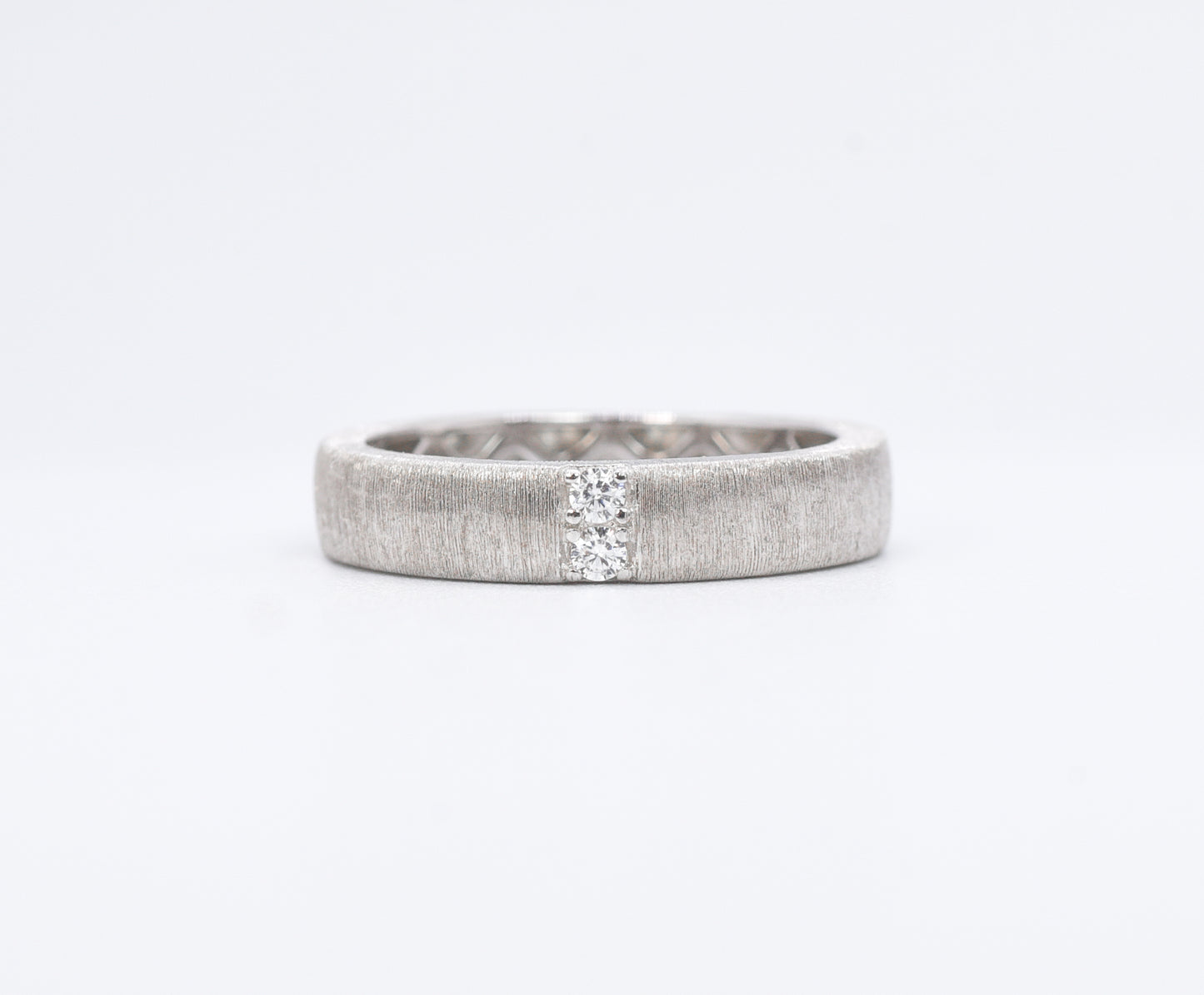 Silver ring with a textured band on a white background