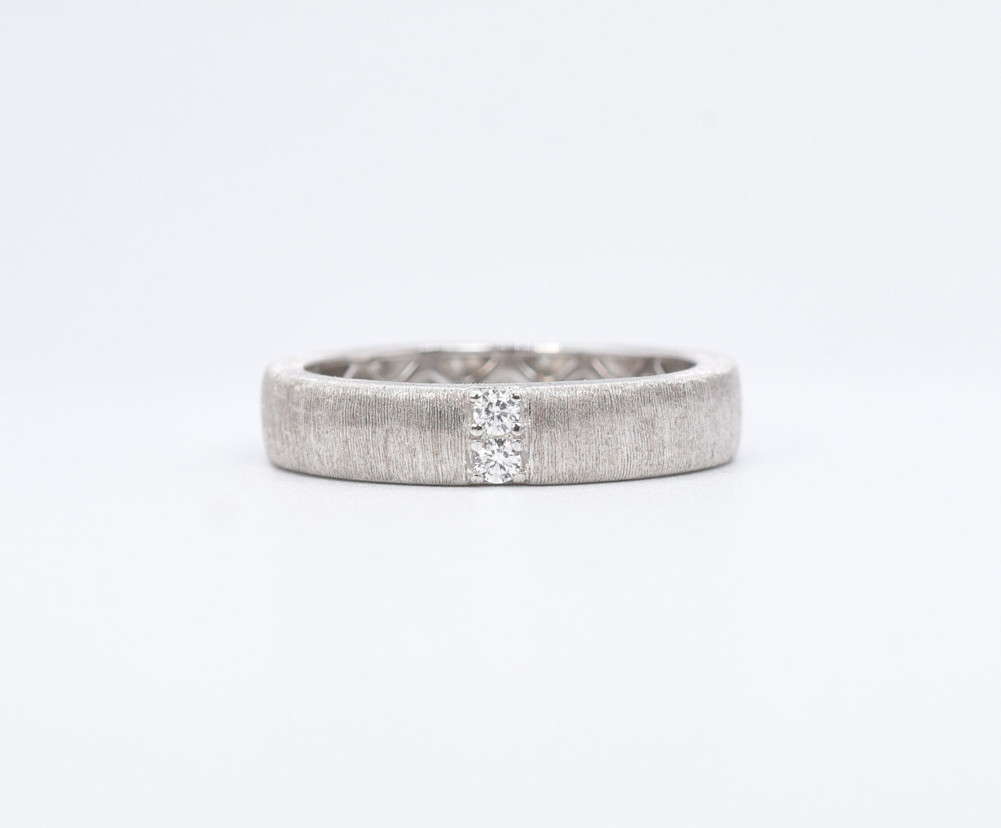 Silver ring with a textured band on a white background