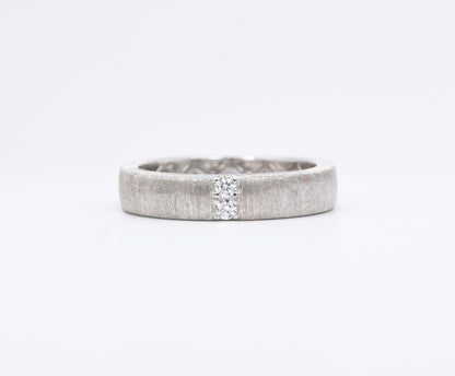 Silver ring with a textured band on a white background