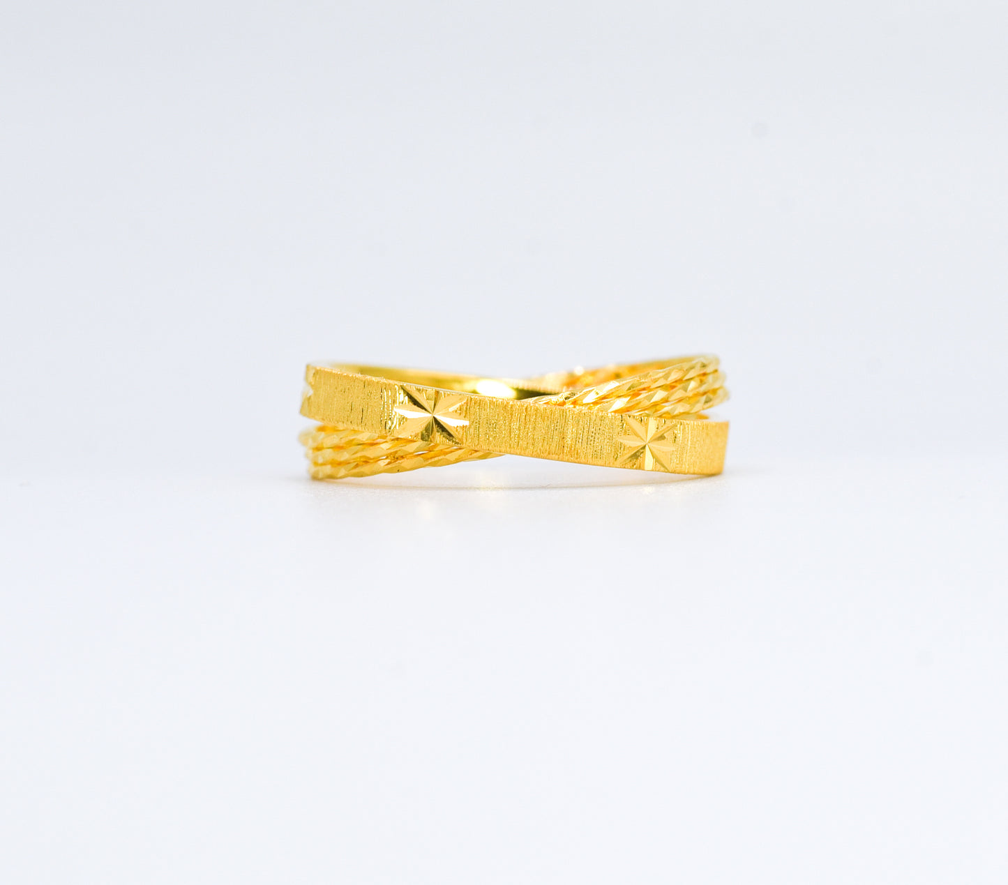 Gold ring with textured design on a white background