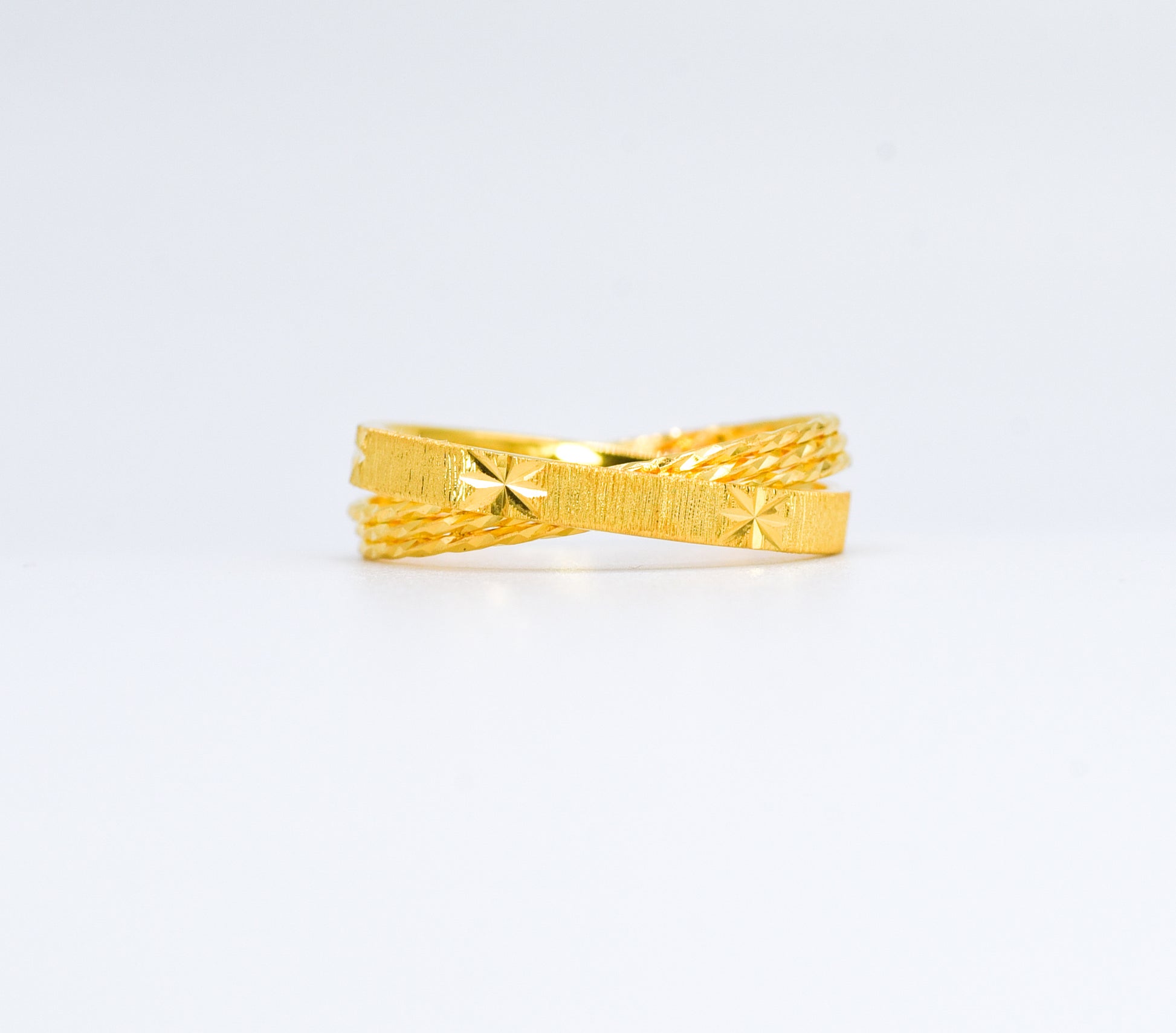 Gold ring with textured design on a white background