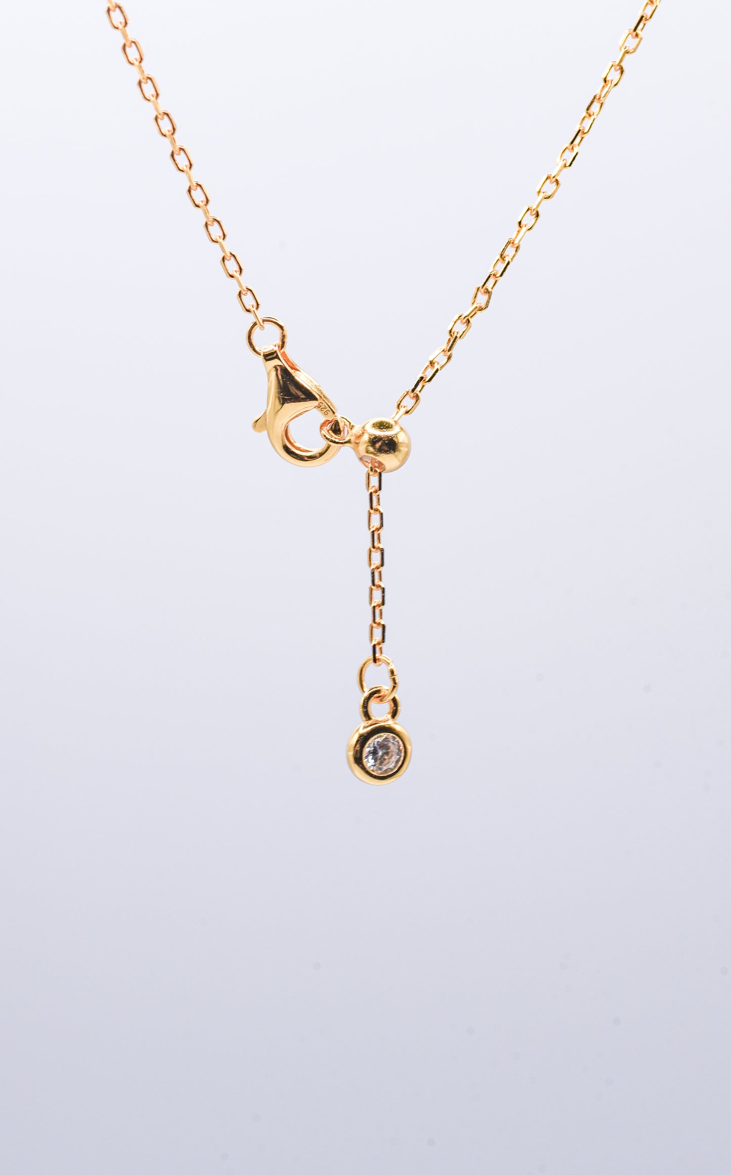Gold color necklace on a light gray background