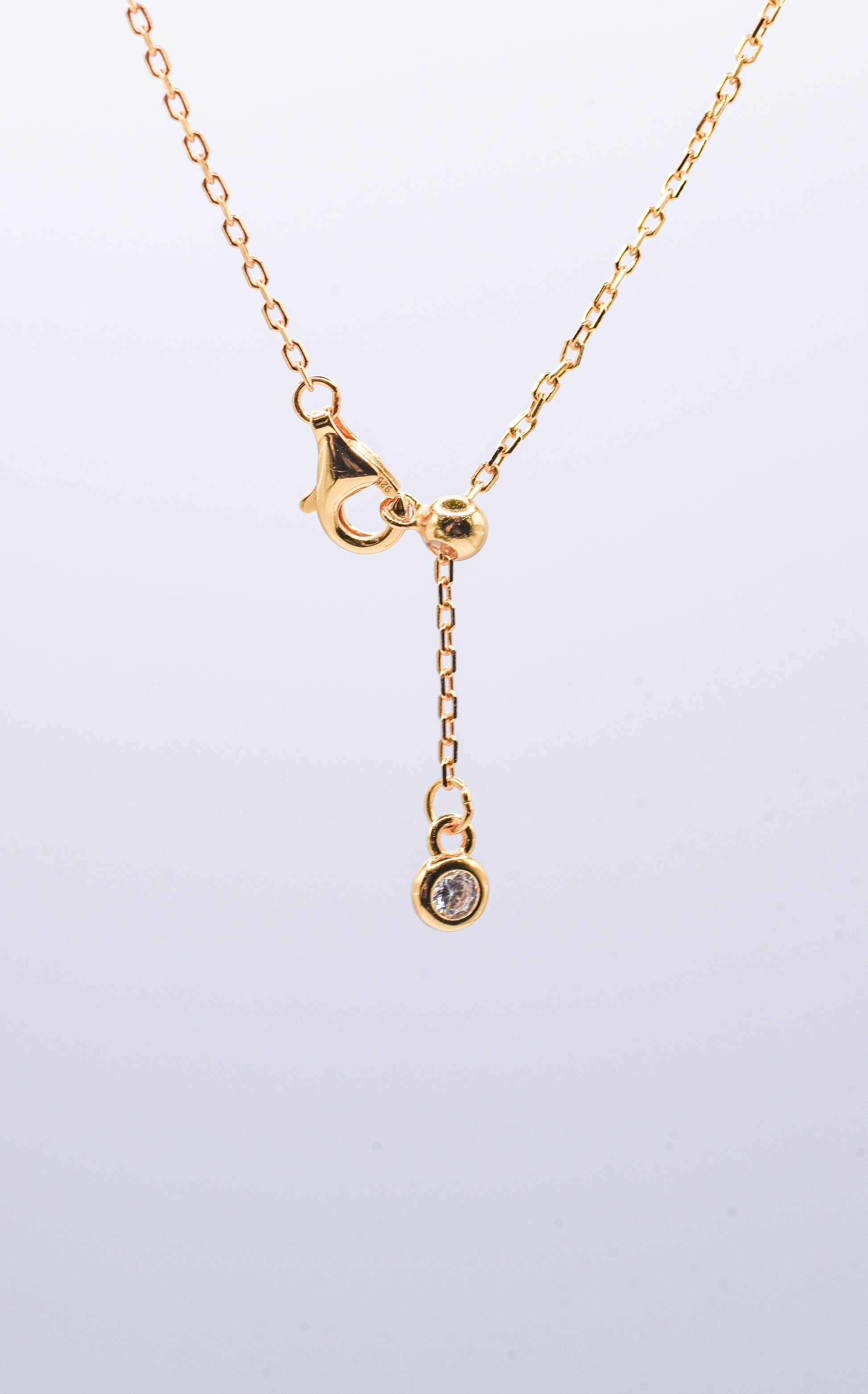 Gold color necklace on a light gray background