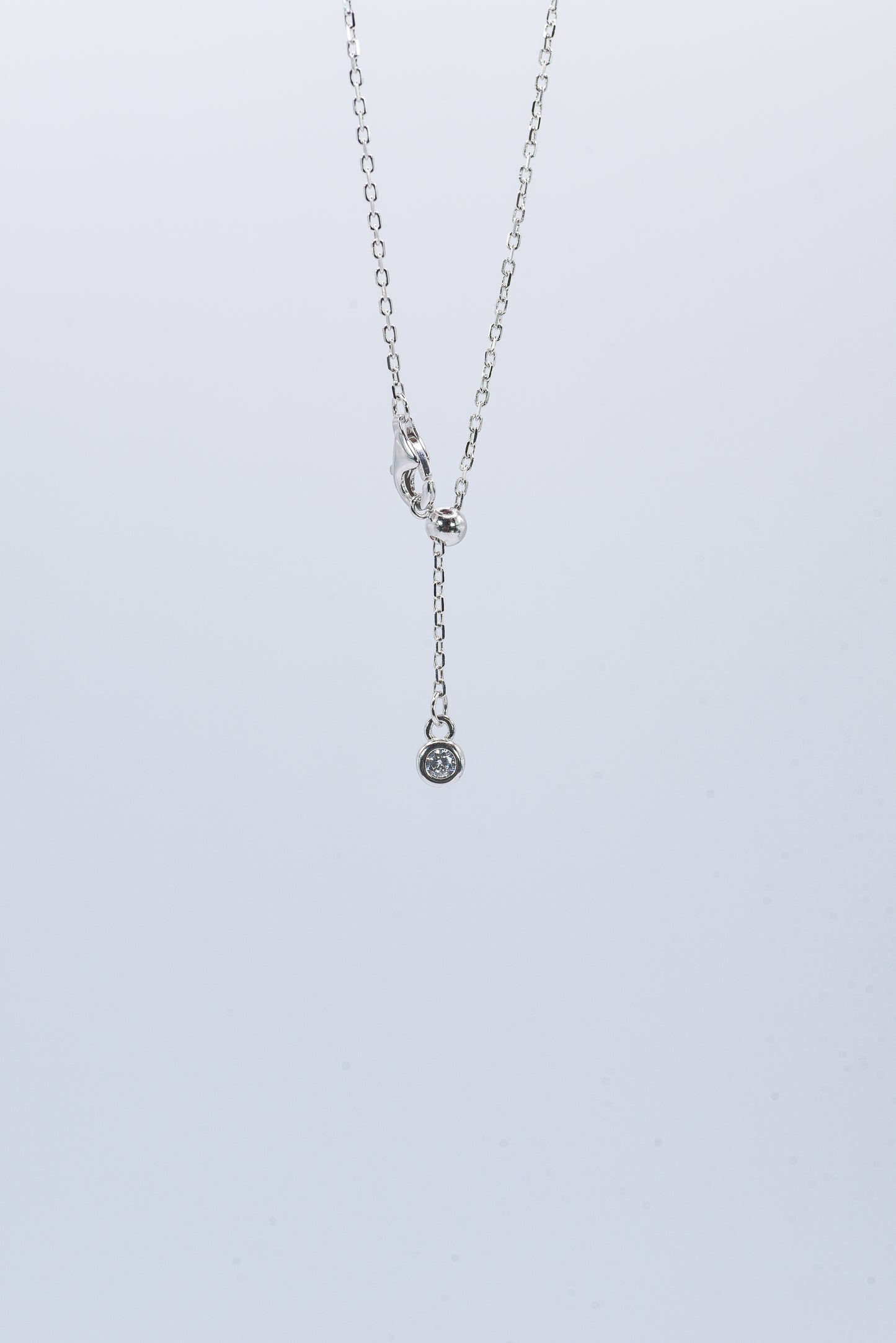 Silver necklace with a small pendant on a light gray background