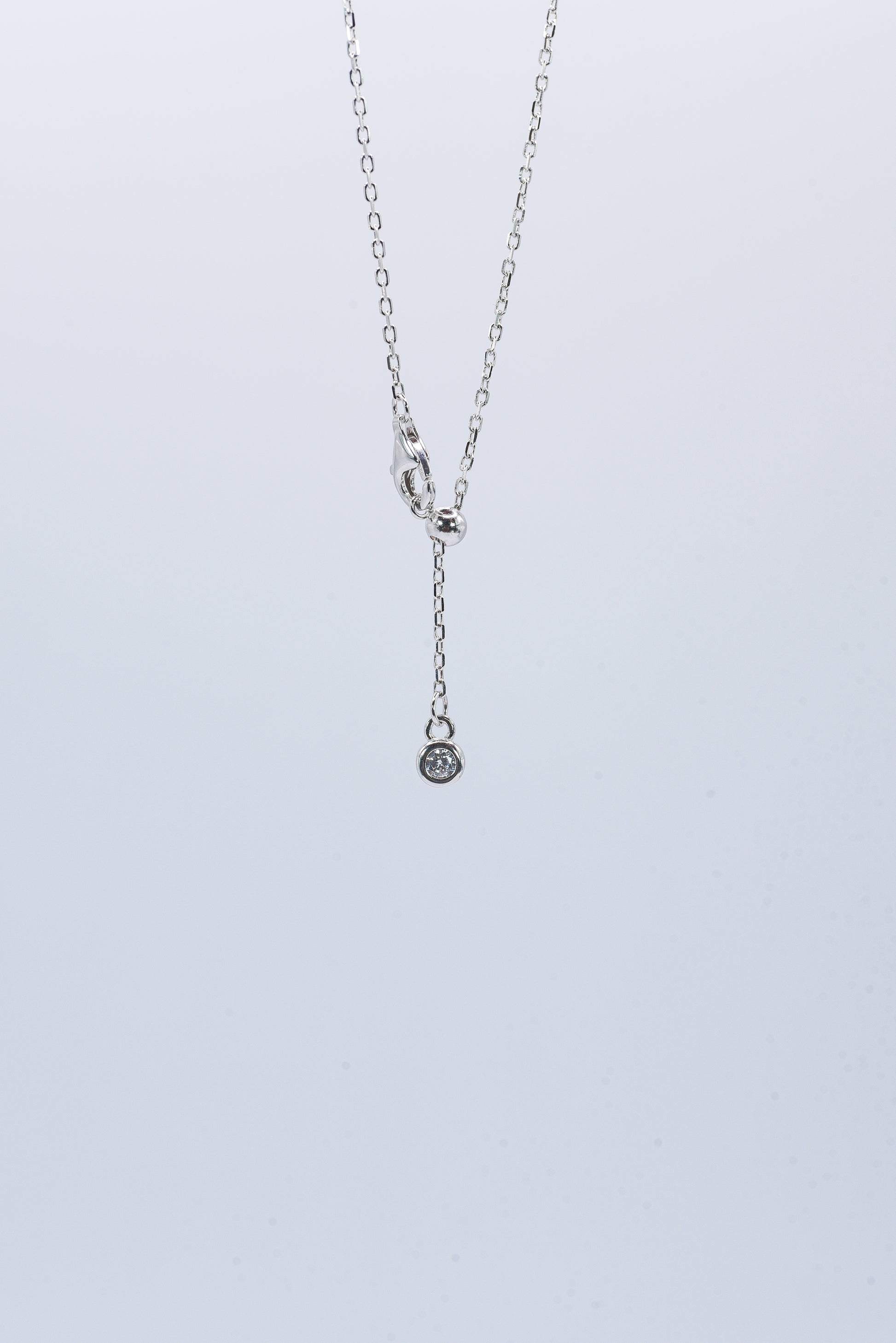 Silver necklace with a small pendant on a light gray background