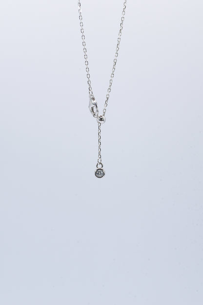 Silver necklace with a small pendant on a light gray background