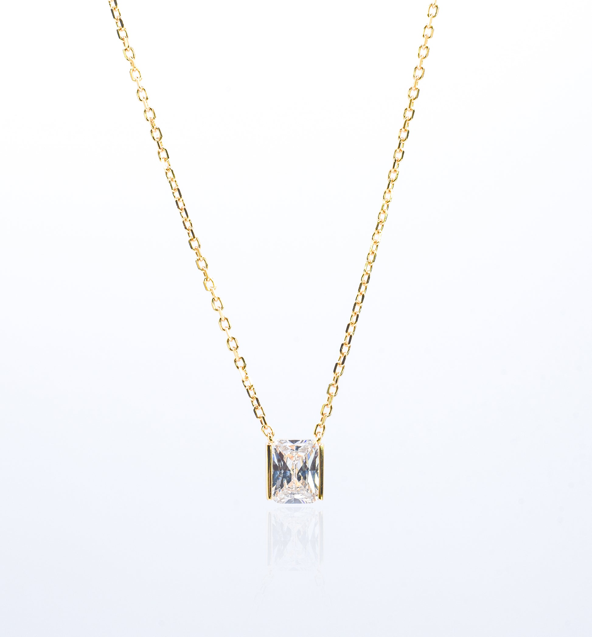 Gold color necklace with a square-cut gemstone pendant on a white background