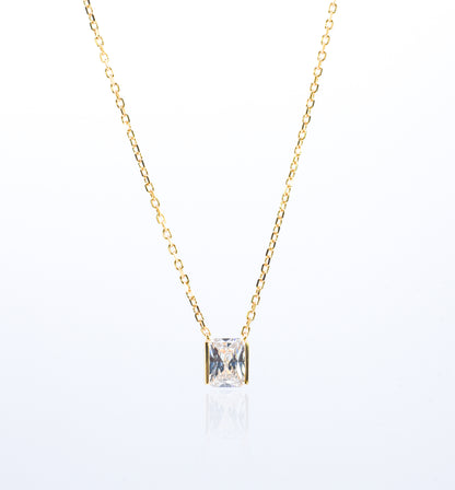 Gold color necklace with a square-cut gemstone pendant on a white background