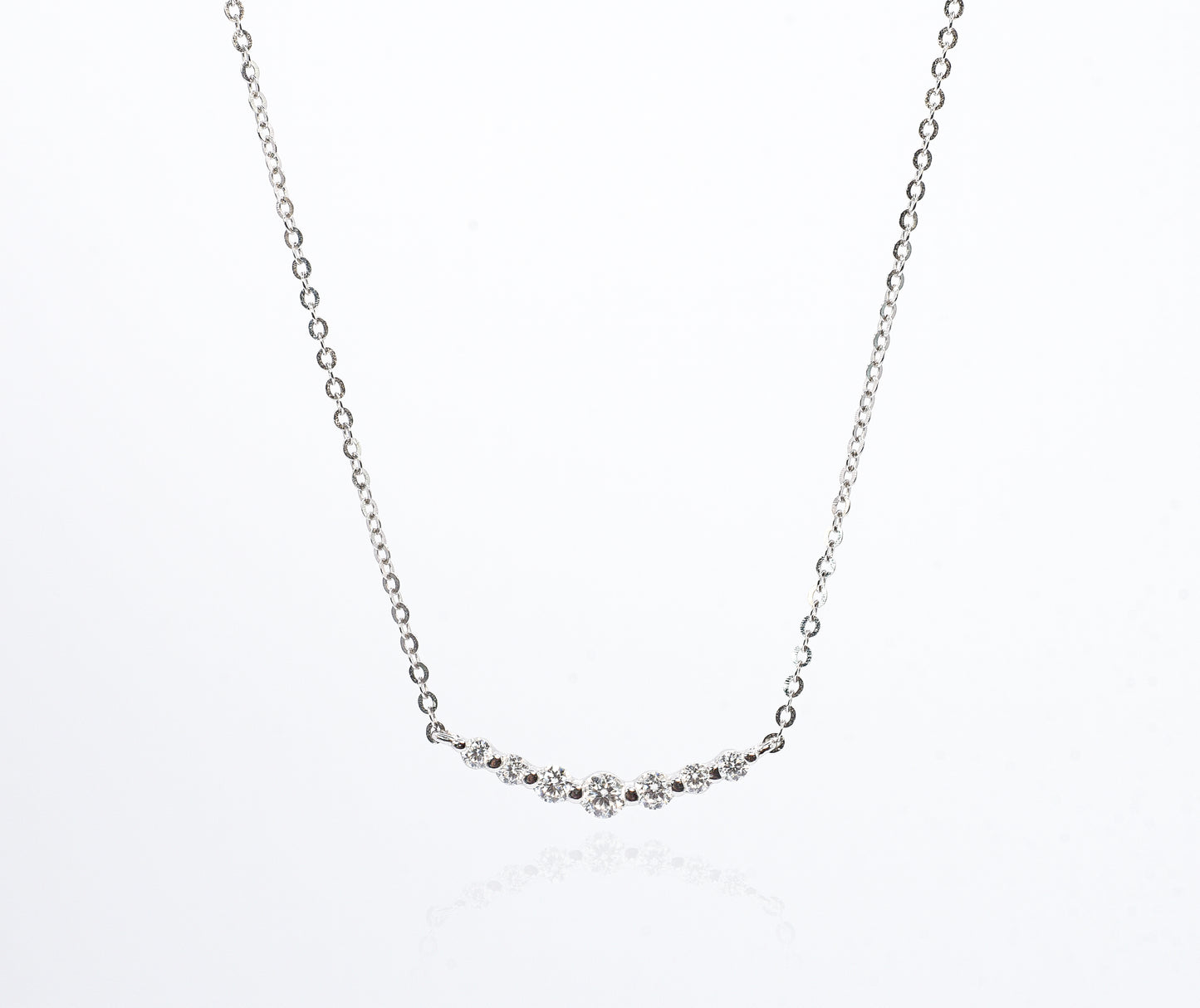 Delicate silver necklace with small Moissanite Stones on a white background