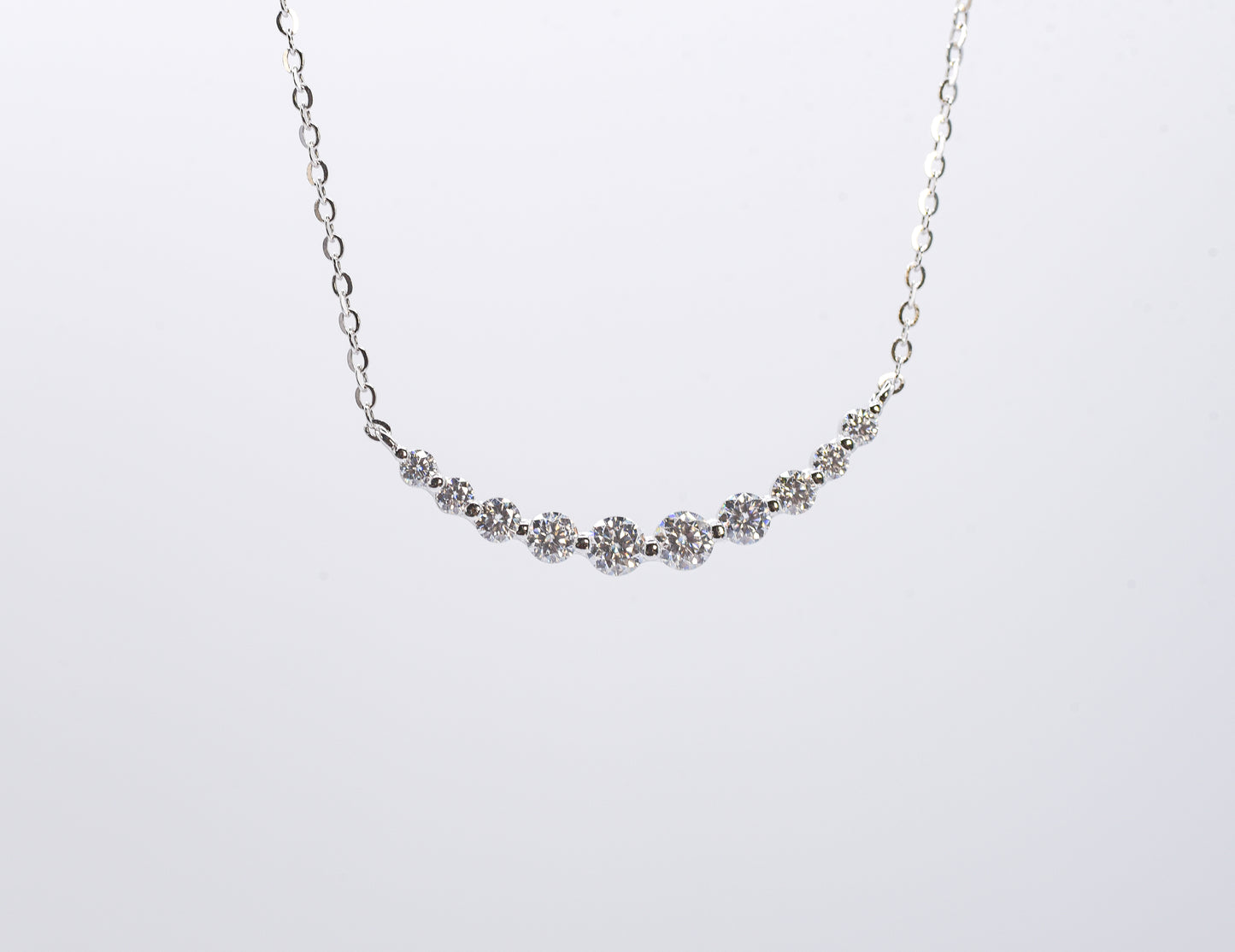 Delicate silver necklace with small gemstones on a white background