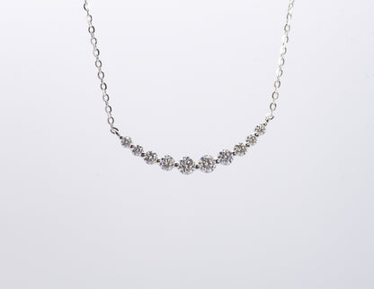Delicate silver necklace with small gemstones on a white background