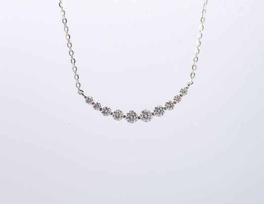 Delicate silver necklace with small gemstones on a white background
