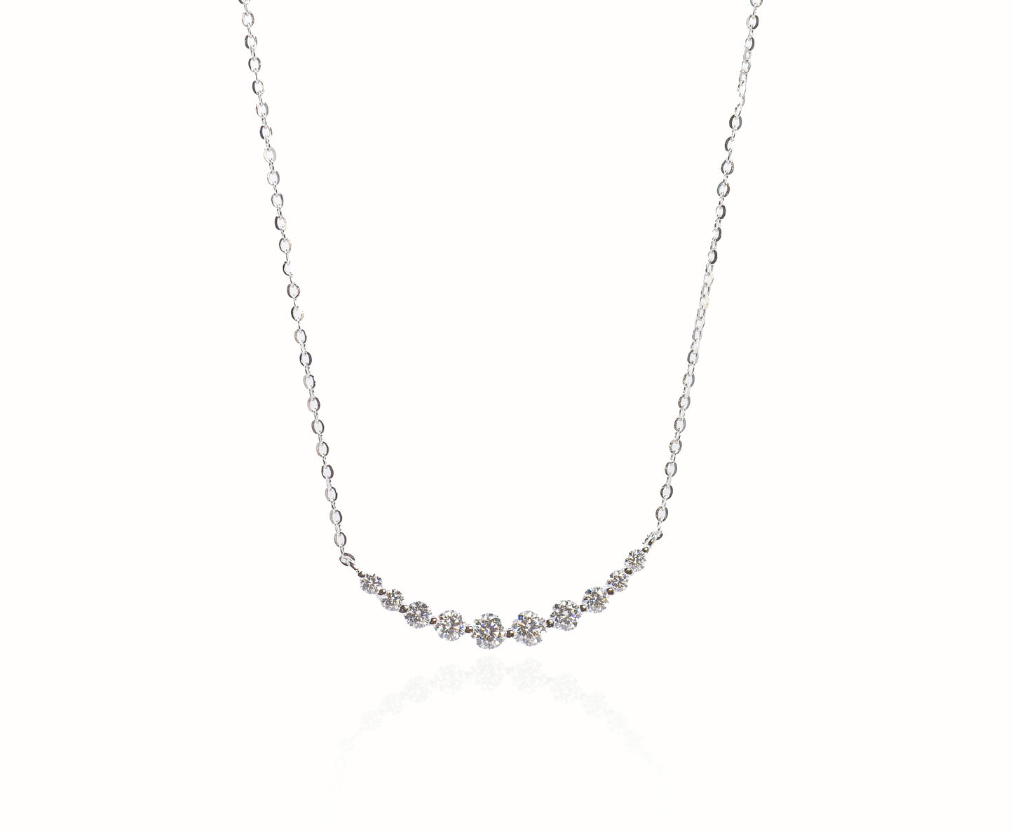 Delicate silver necklace with small gemstones on a white background