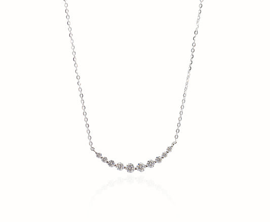 Delicate silver necklace with small gemstones on a white background