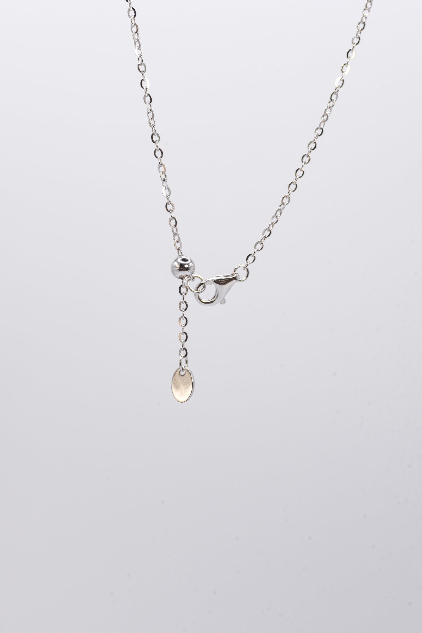 Silver necklace with a small pendant on a light gray background