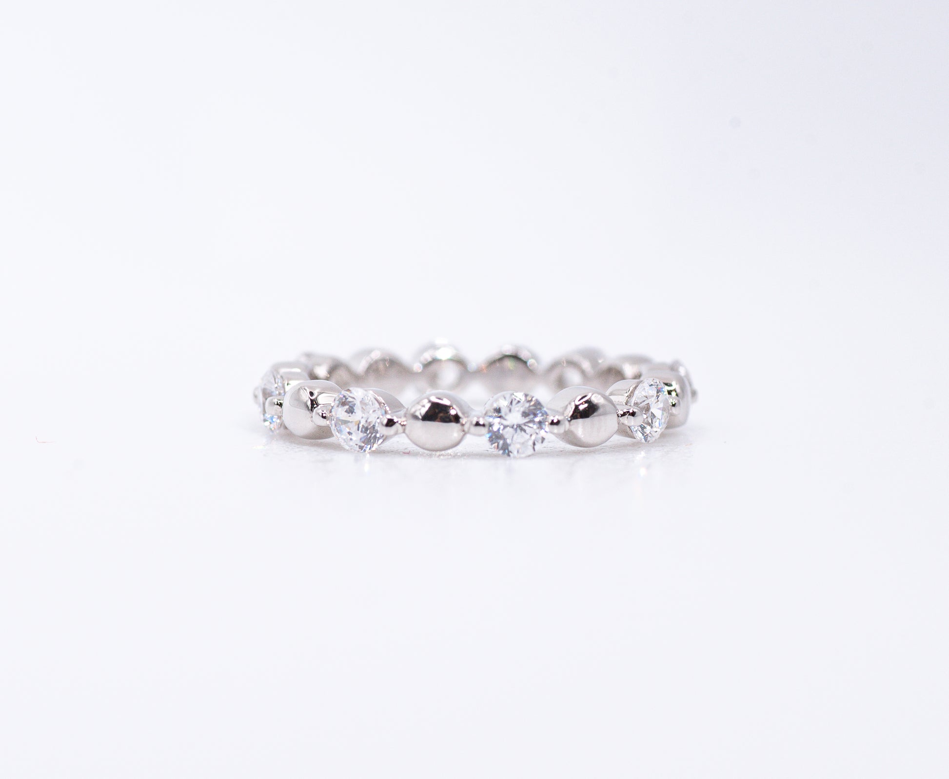 Silver ring with clear gemstones on a white background