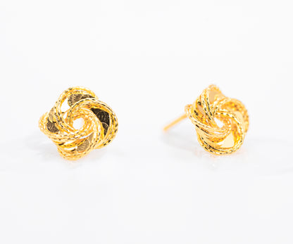 Pair of gold color knot earrings on a white background