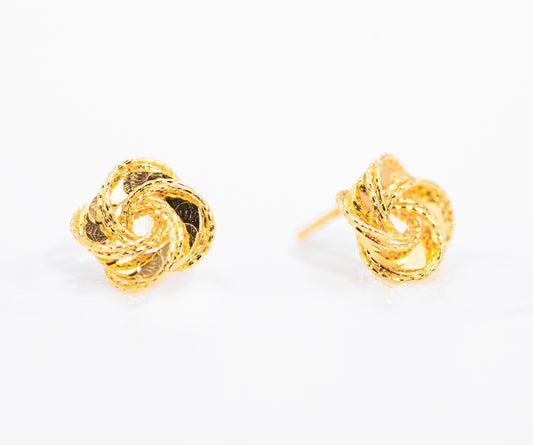 Pair of gold color knot earrings on a white background