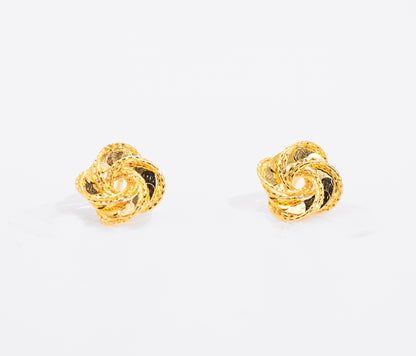 Pair of gold color knot earrings on a white background