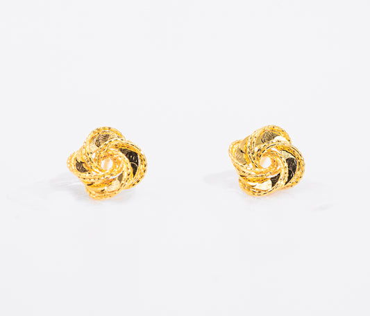 Pair of gold color knot earrings on a white background