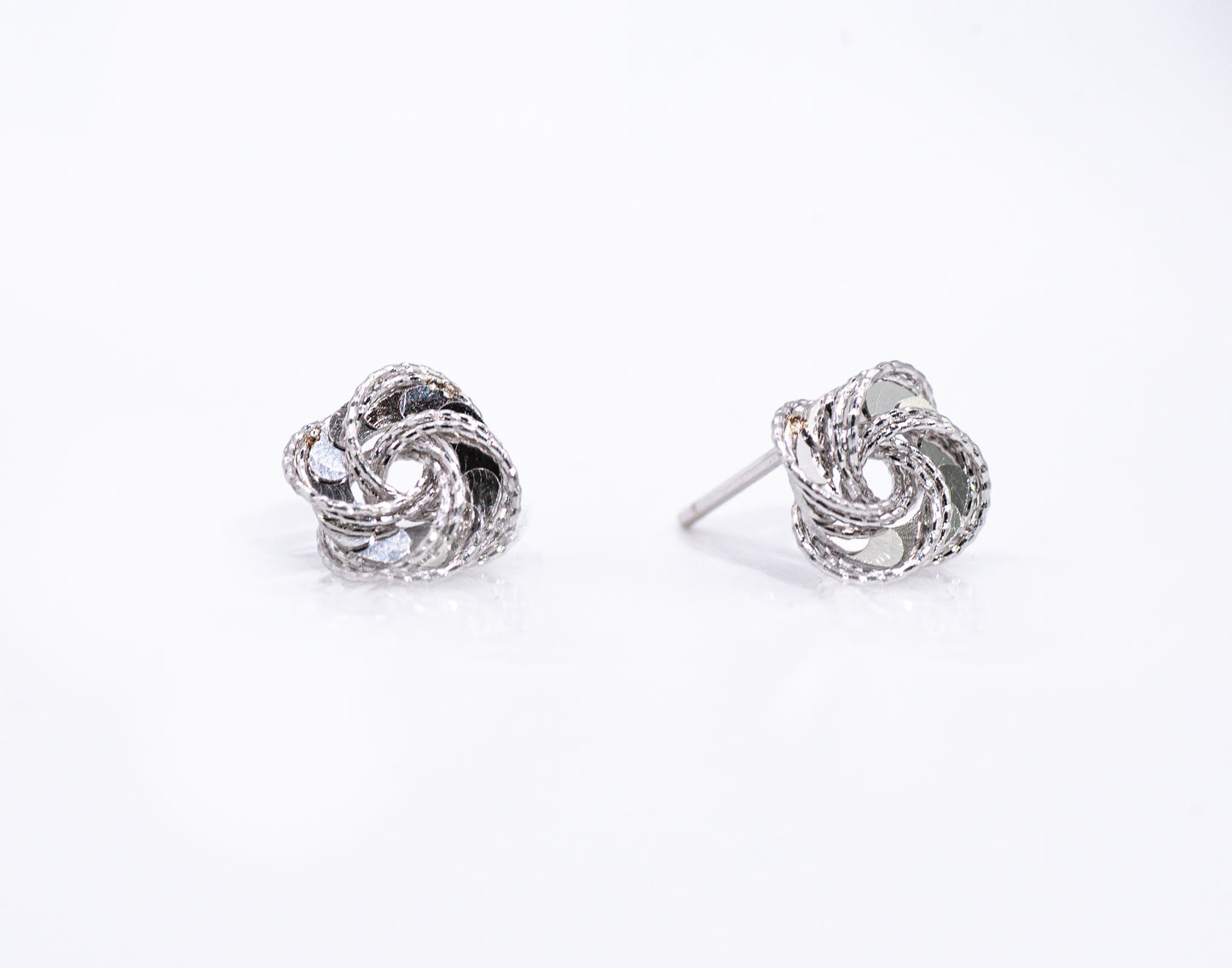 Pair of silver knot earrings on a white background
