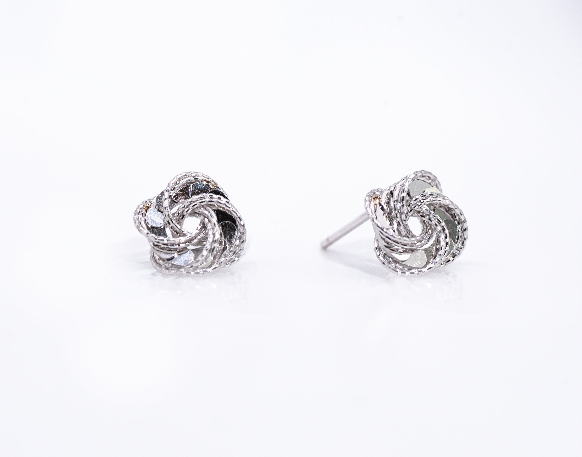 Pair of silver knot earrings on a white background