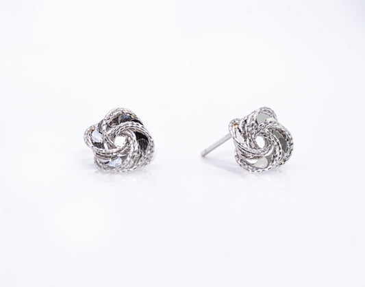 Pair of silver knot earrings on a white background