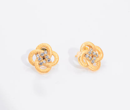 Gold flower shaped earrings with gemstones on a white background