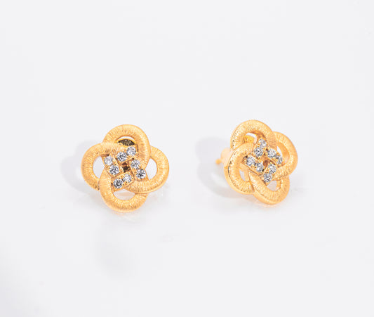 Gold flower shaped earrings with gemstones on a white background