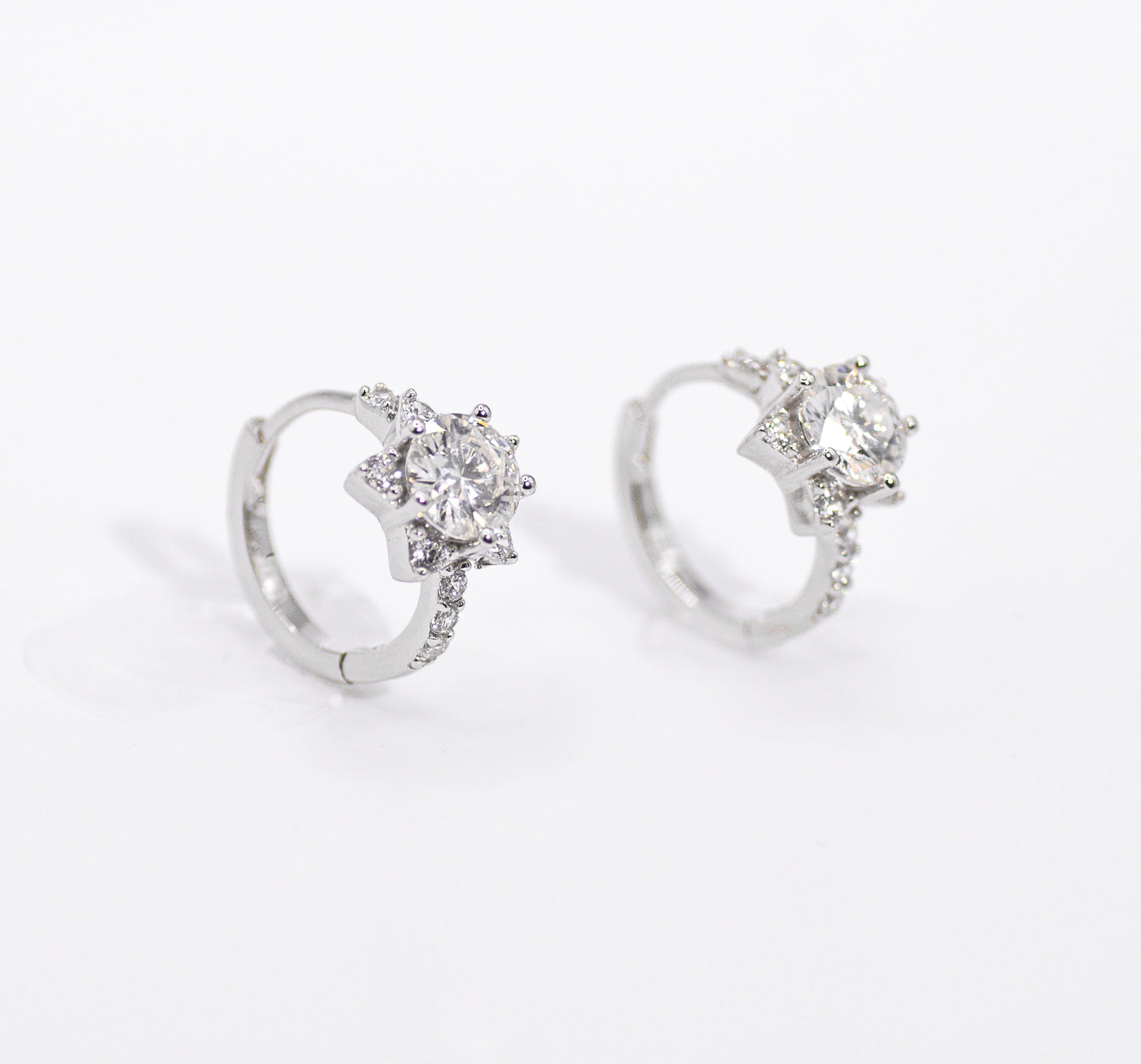 Pair of silver earrings with clear gemstones on a white background