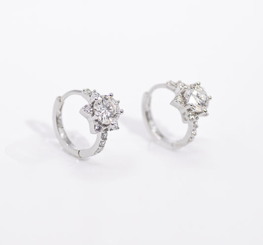 Pair of silver earrings with clear gemstones on a white background