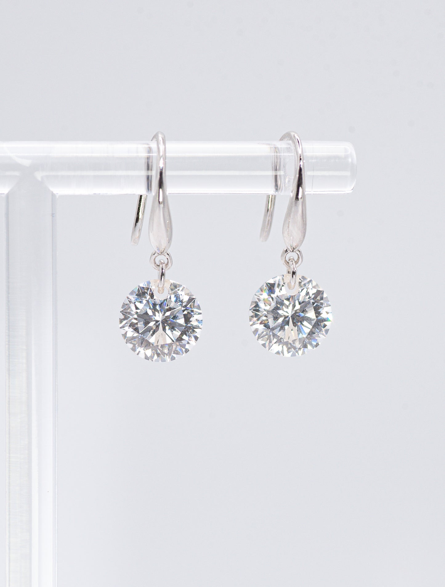 Pair of silver earrings with clear gemstones on a white background