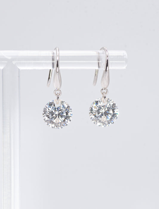 Pair of silver earrings with clear gemstones on a white background