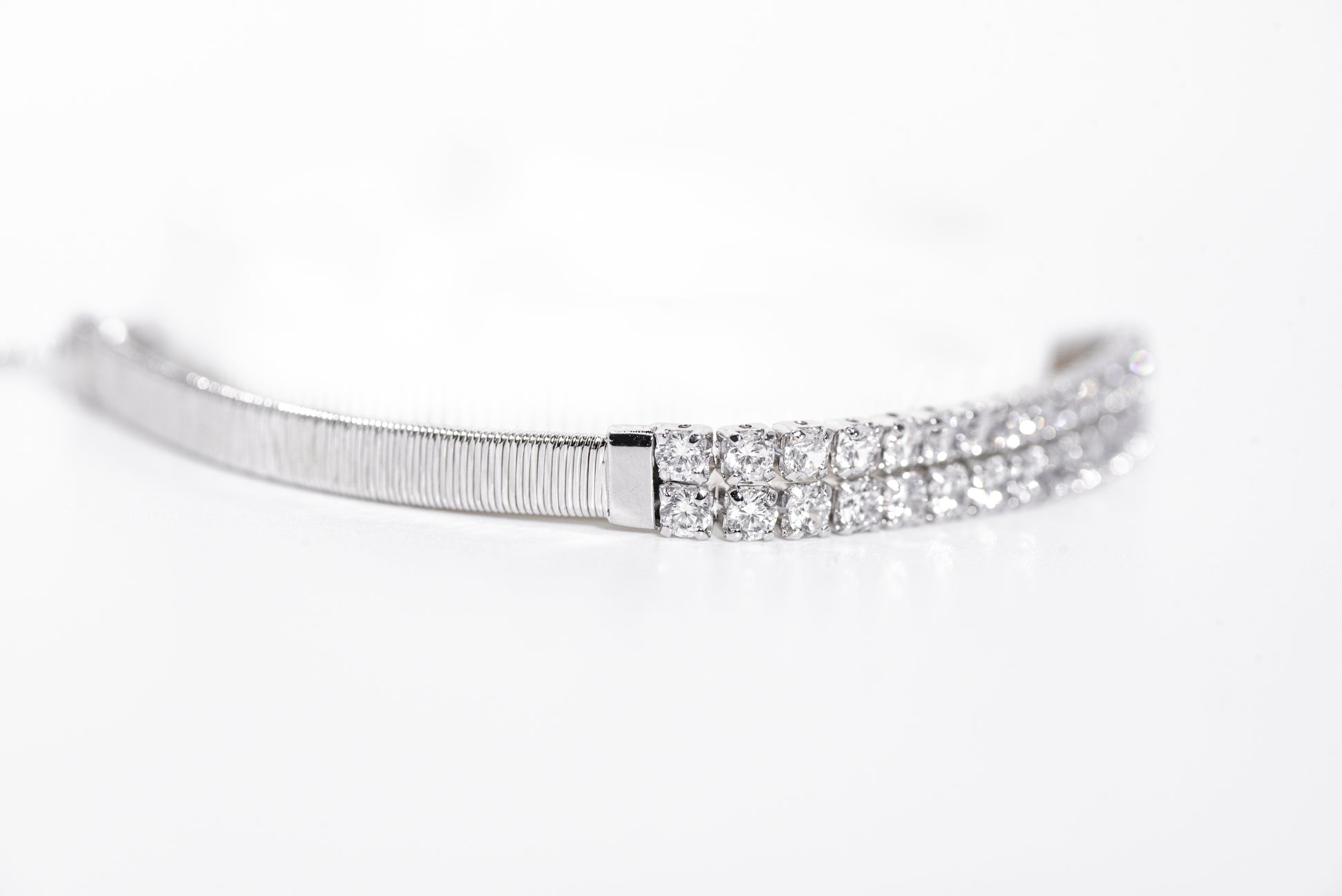 Silver bracelet with clear gemstones on a white background