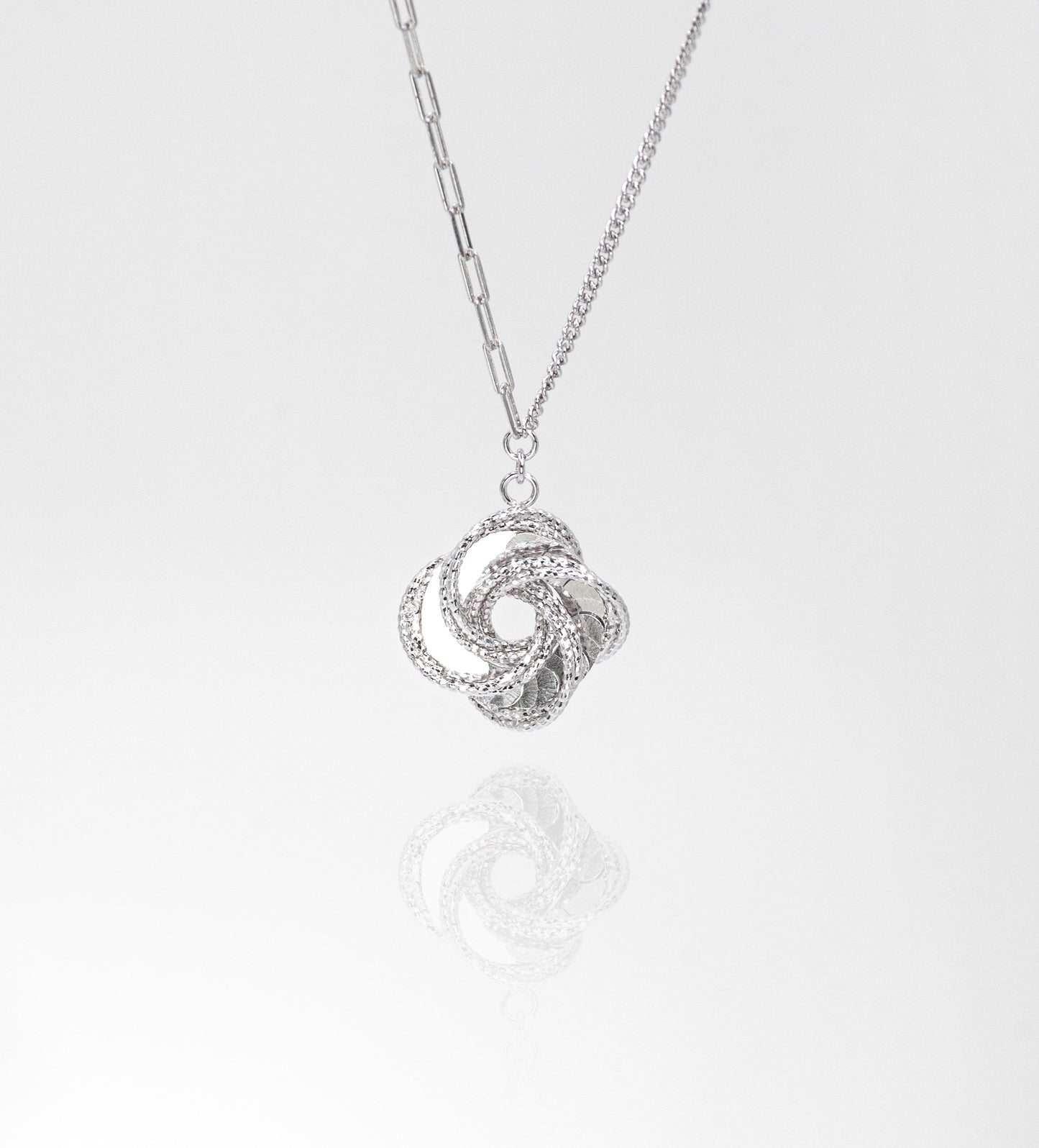 Silver necklace with a intricate pendant on a light gray background