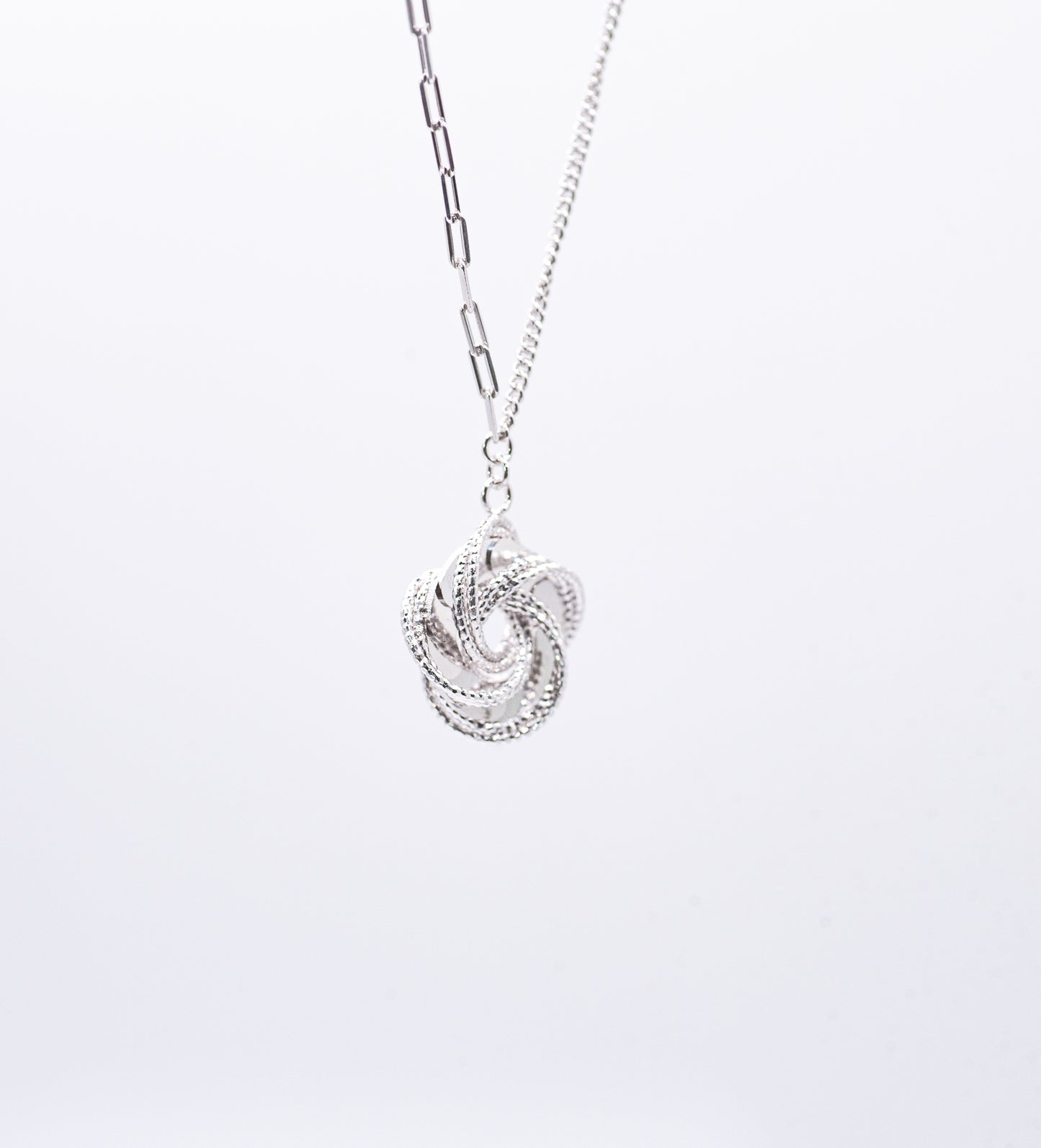 Silver necklace with a intricate pendant on a light gray background