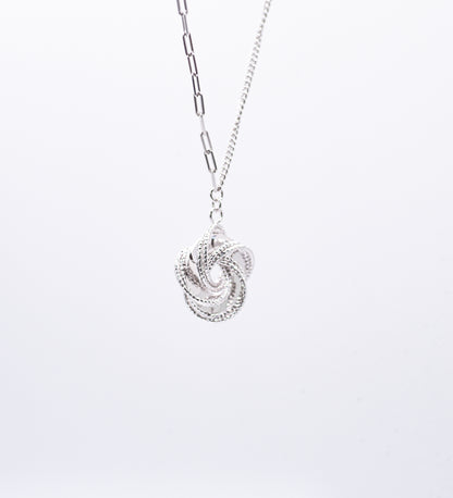 Silver necklace with a intricate pendant on a light gray background
