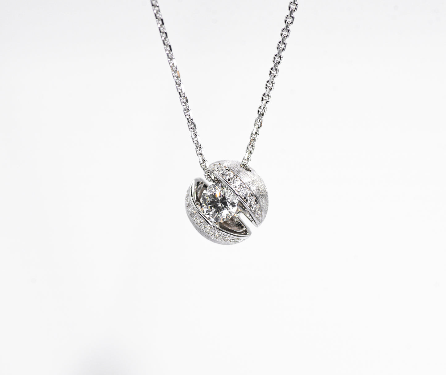 Silver necklace with a round pendant on a white background