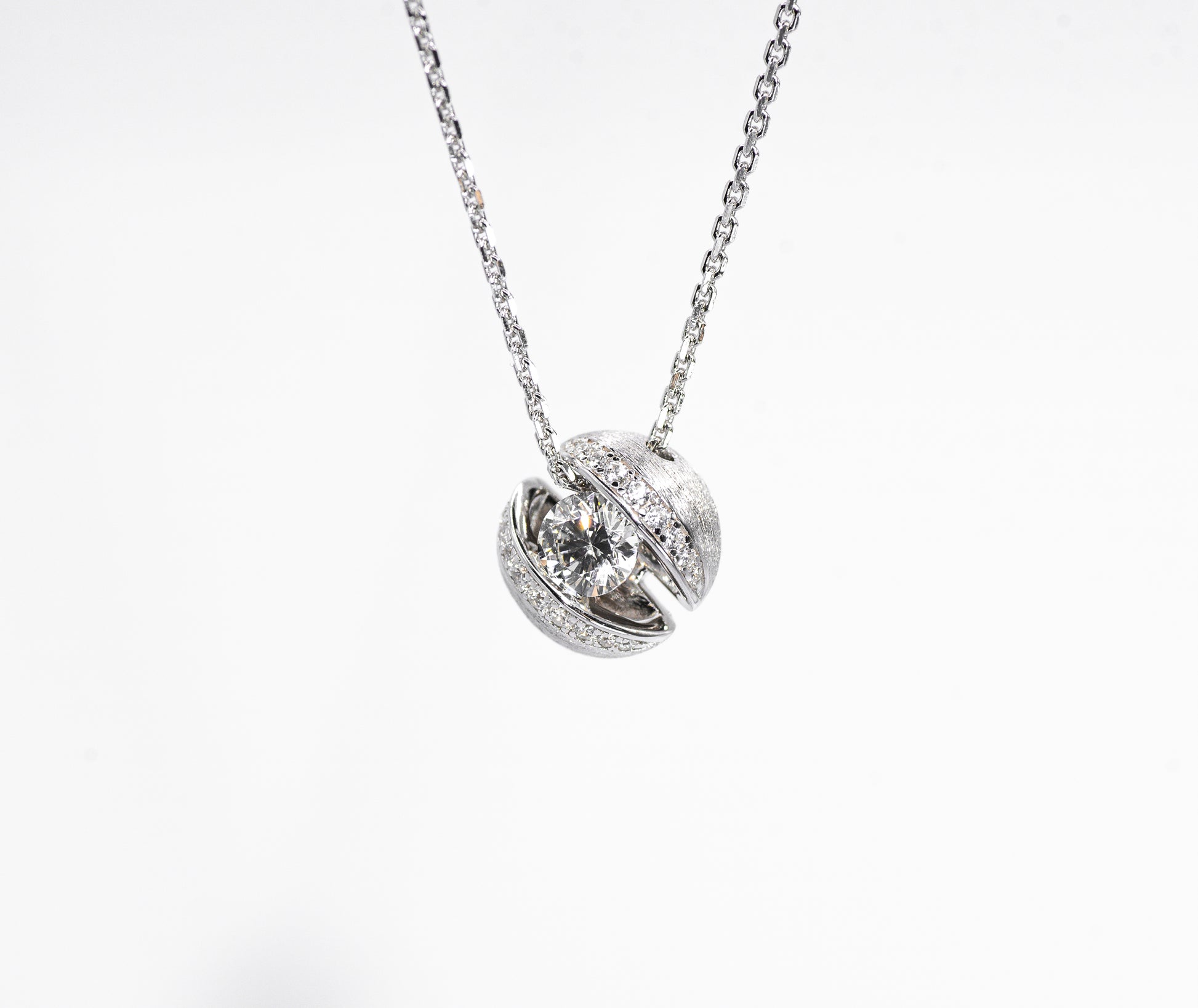 Silver necklace with a round pendant on a white background