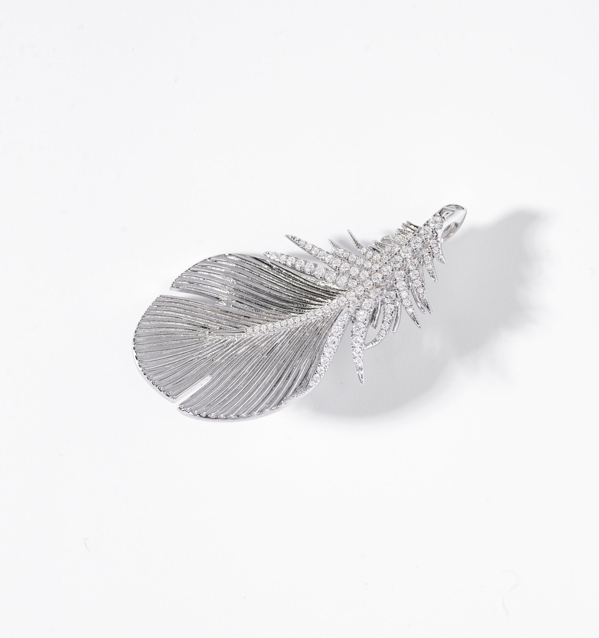 Feather-shaped jewelry piece with gemstones on a white background