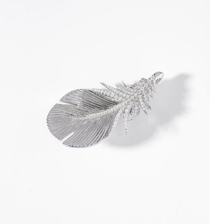 Feather-shaped jewelry piece with gemstones on a white background