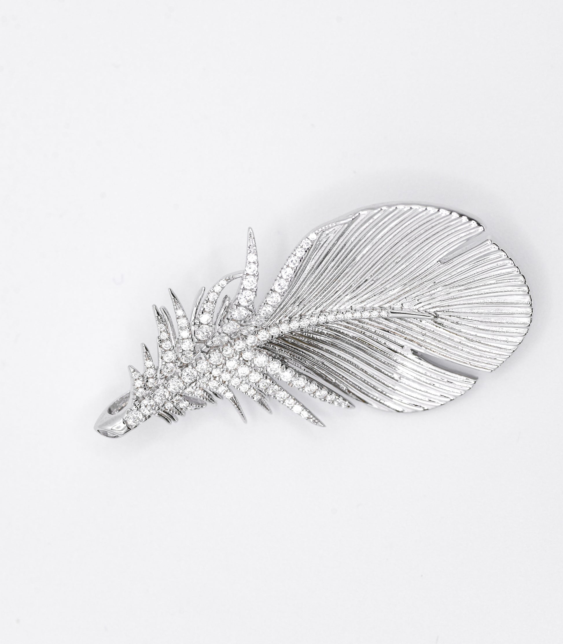 Silver feather-shaped brooch with gemstones on a white background