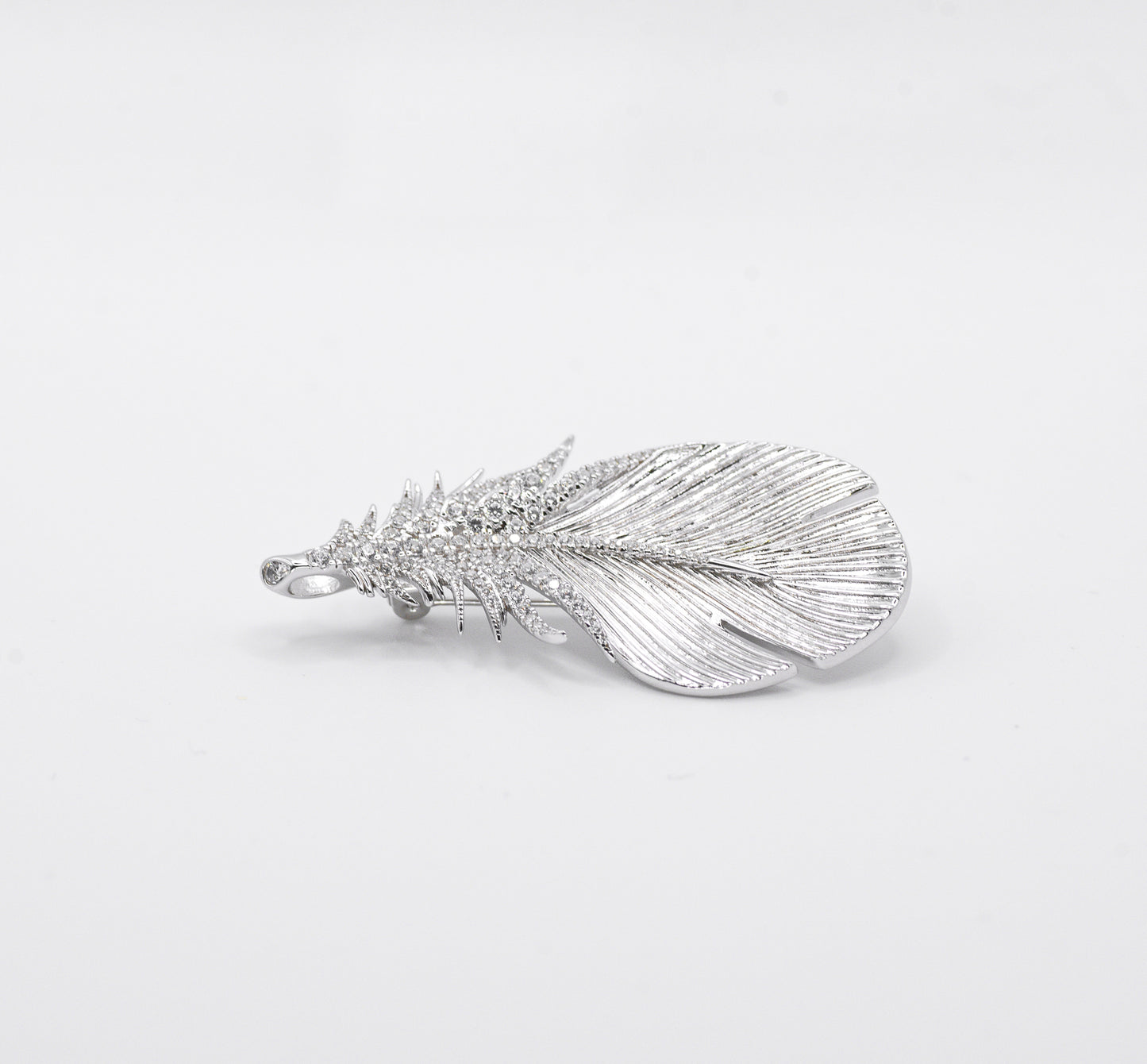 Silver feather-shaped pendant on a light gray background