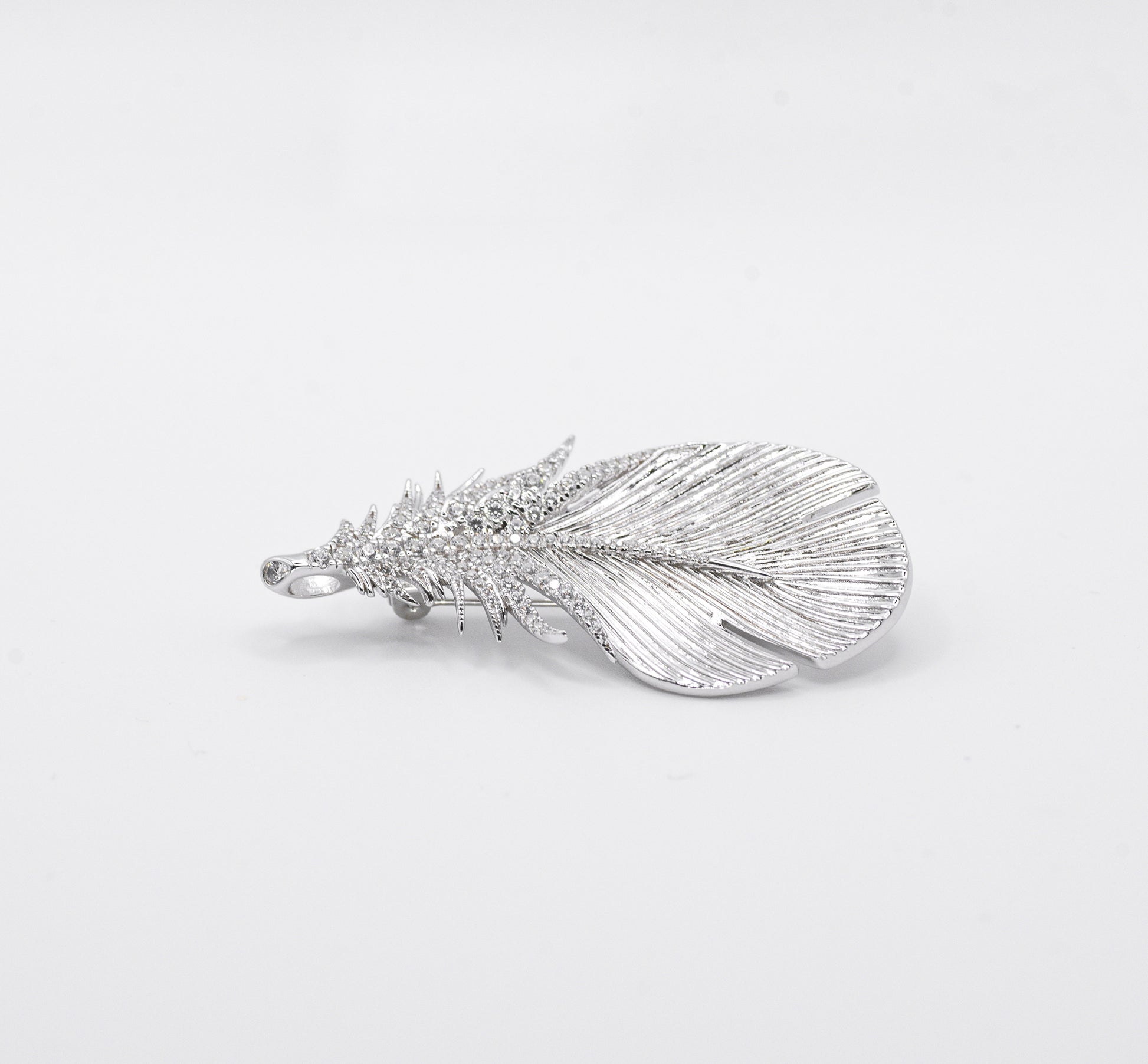 Silver feather-shaped pendant on a light gray background