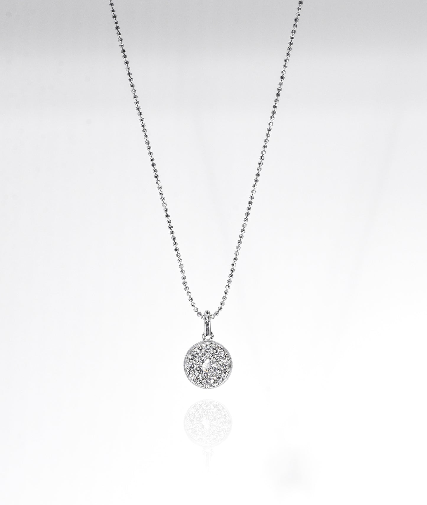 Silver necklace with a round pendant on a light gray background