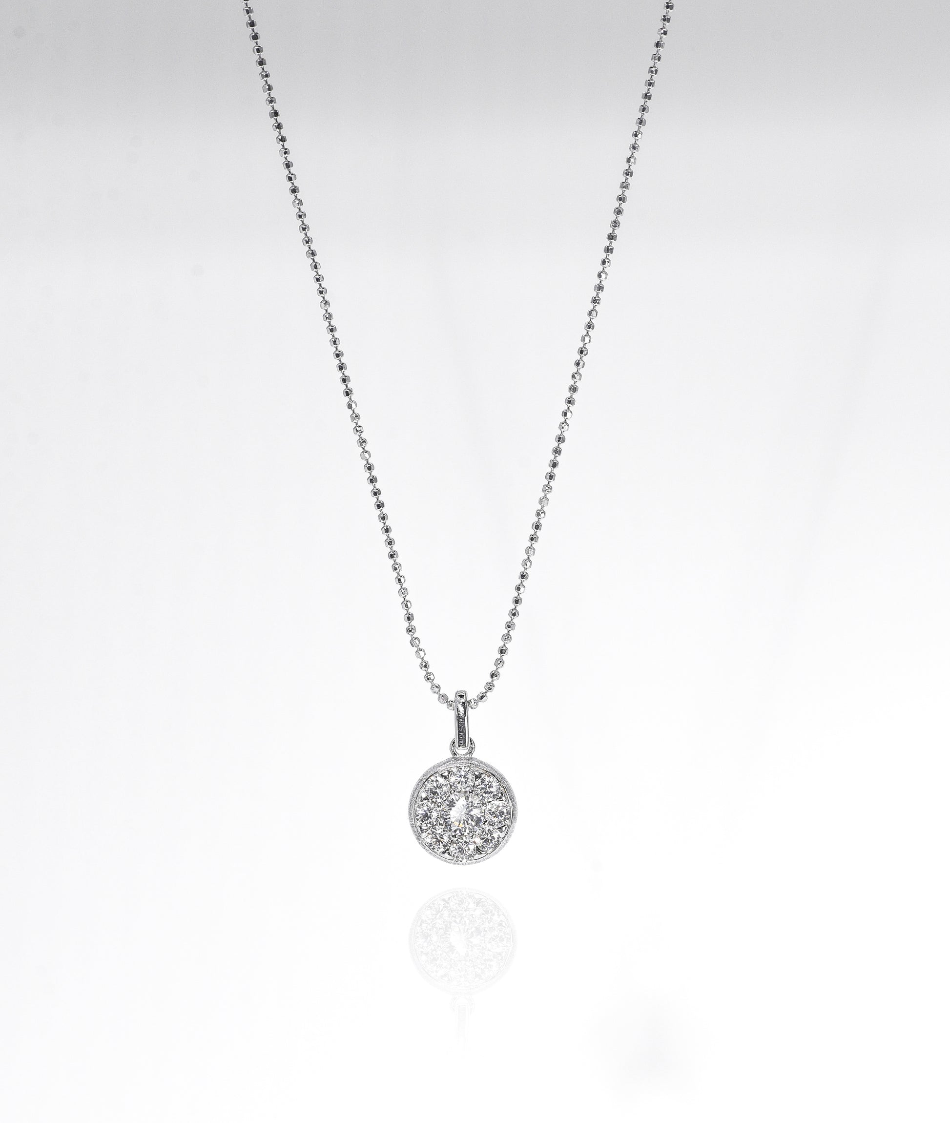 Silver necklace with a round pendant on a light gray background