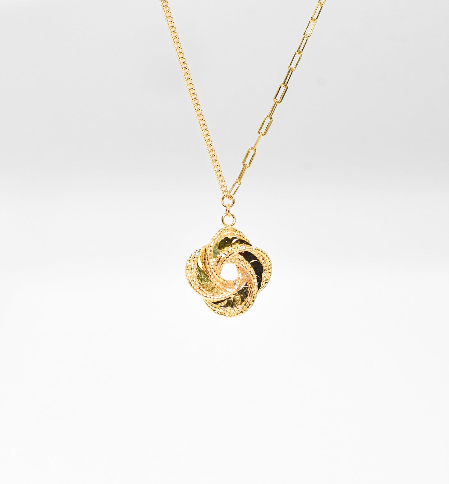 Gold color necklace with a unique pendant on a light gray background