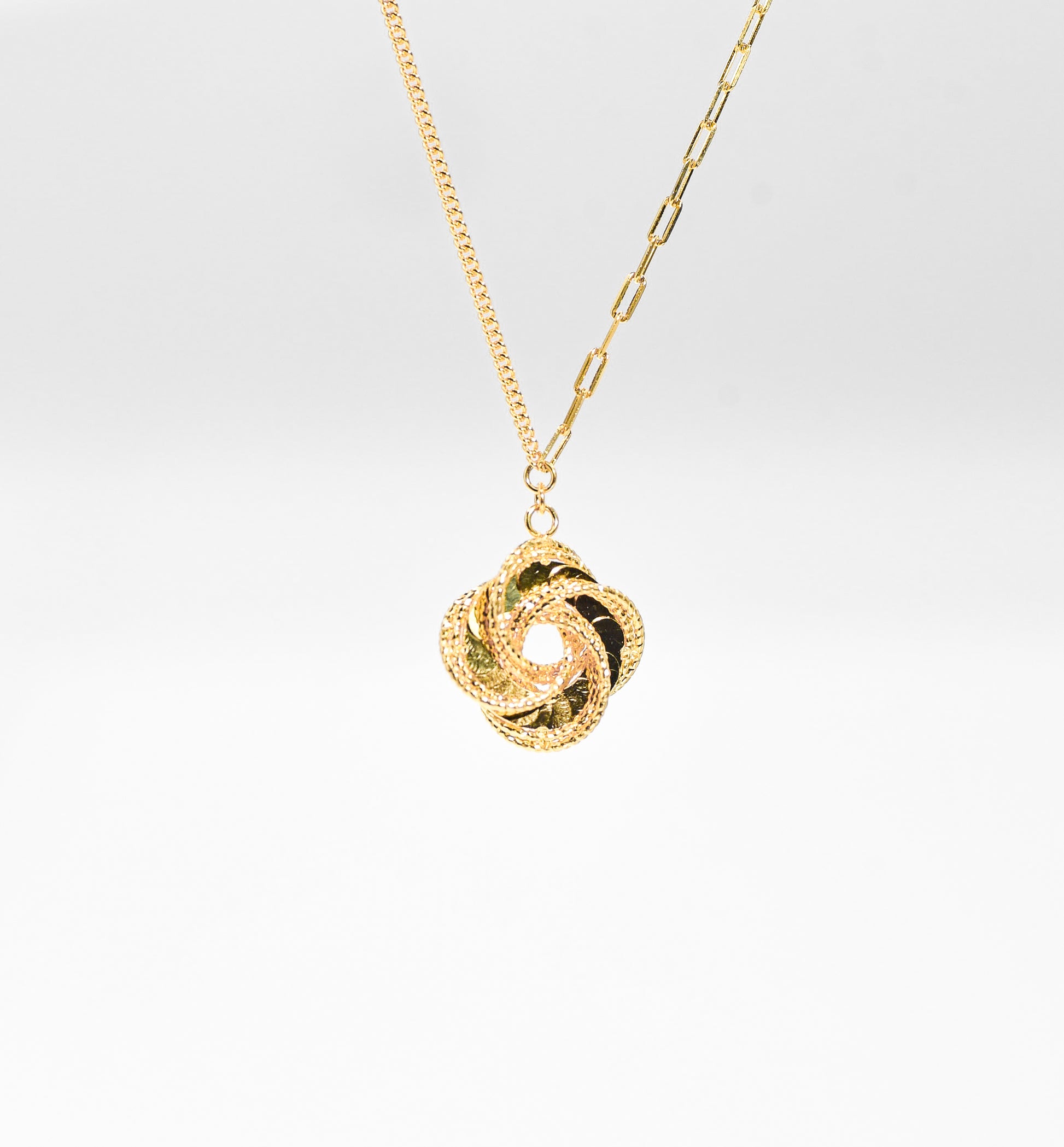 Gold color necklace with a unique pendant on a light gray background