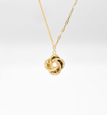 Gold color necklace with a unique pendant on a light gray background