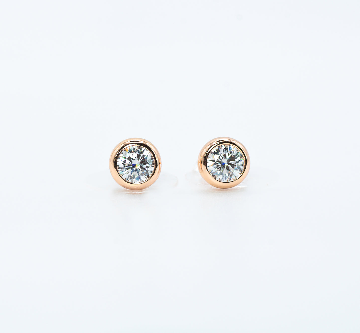 Pair of rose gold color with  Cubic Zirconia stud earrings on a white background